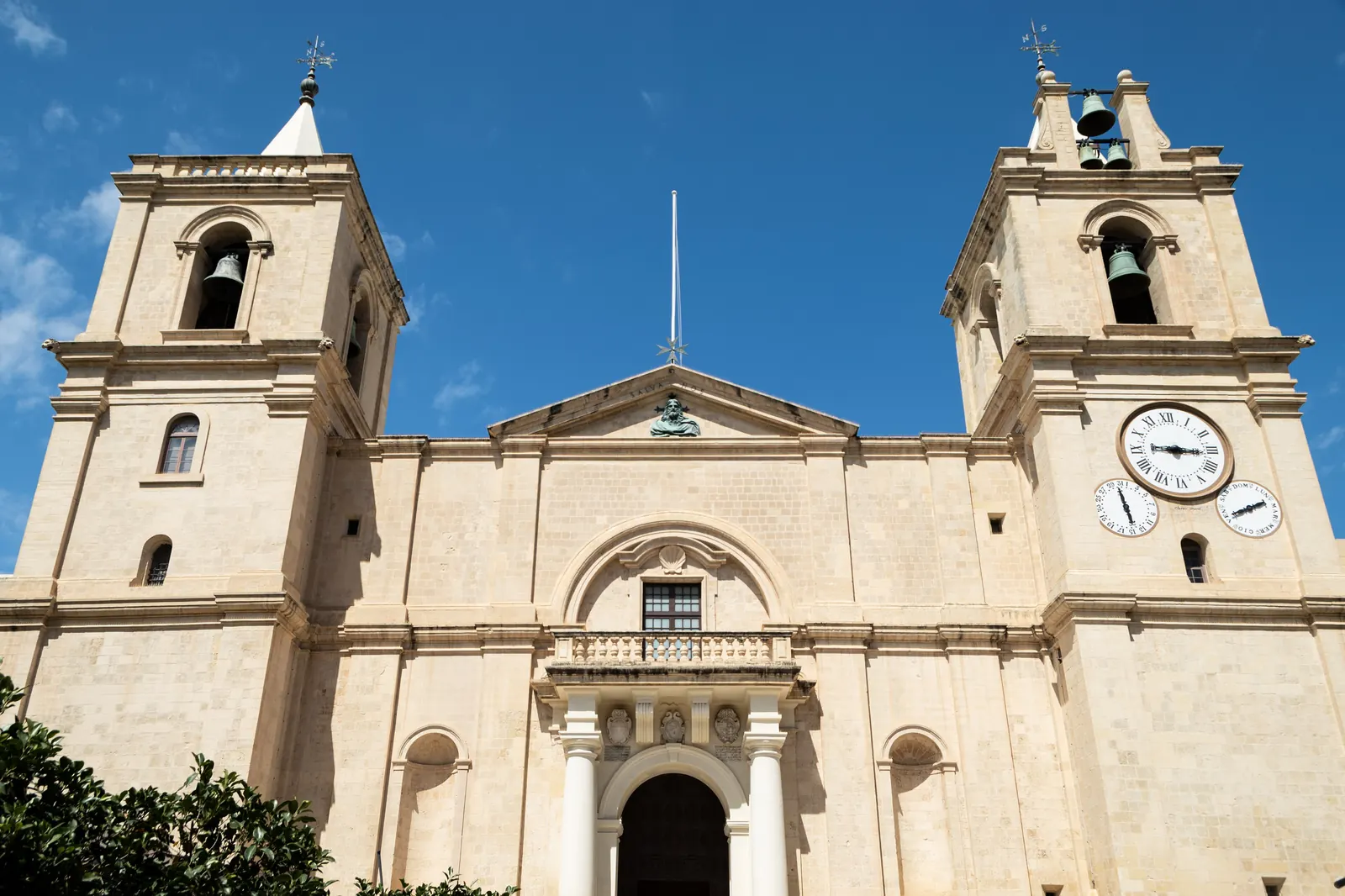 The plain limestone front of St John's Co-Cathedral in Valletta, with two bell towers and a balcony over the doorway